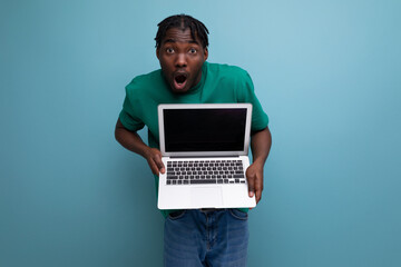 american young brunette man in casual t-shirt shows laptop screen with mockup for web page