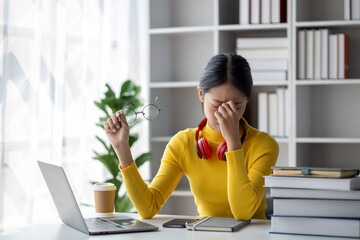 Teenage woman sitting in white room with laptop, she has stress, she is a student studying online with laptop at home, university student studying online, online web education concept.