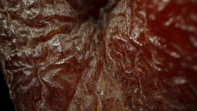 Single dried apricot on a black background, macro zoom.