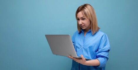 Fototapeta premium attentive millennial woman in casual shirt holding a laptop in her hands on a blue isolated background with copy space