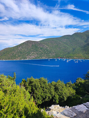 Obraz premium This stunning aerial view showcases the vivid blue Mediterranean Sea with boats, framed by mountains, and enveloped in lush trees. Embrace nature's captivating harmony. The essence of Greek tourism.