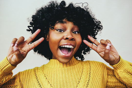happy black woman smiling with open mouth and fingers in victory sign