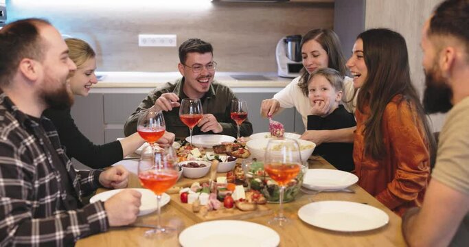 A group of beautiful millennial youngsters joyfully serve themselves from the delicious spread of dishes laid out on the table. They exude happiness and cheerfulness as they fill their plates.