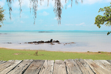 Wooden floor, wooden table on the beach with blue sea and sky background.