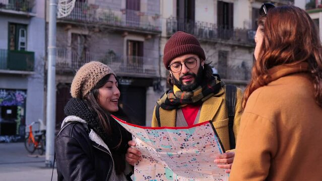 young lost tourist couple asking a local friendly person for directions, she shows them on a map the route they have to take. Friends on a journey trip exploring a foreign city on a weekend travel