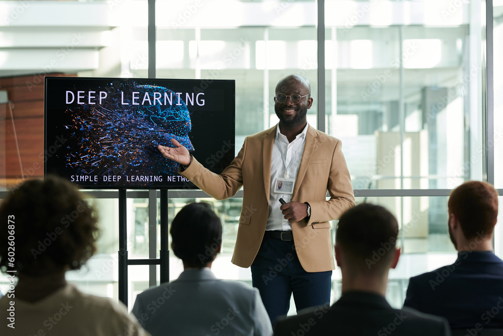 Poster happy young confident teacher or lecturer pointing at interactive board with slide illustrating digi