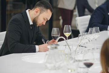 Young man sommelier tasting white wine during study in wine school. Alcoholic beverages degustation. Professional occupation.