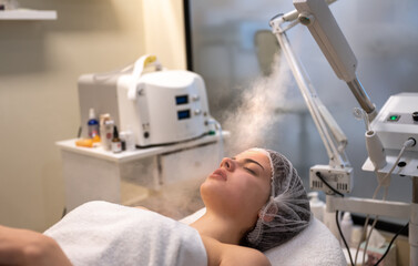 Beautiful woman having treatment of face with ozone facial steamer in beauty clinic.