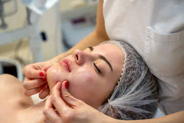 Close up of beautiful young woman getting a face massage treatment at beauty clinic.