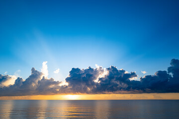 Naklejka na ściany i meble Sunset on tropical beach sea ocean with sunrise clouds. Banner for travel vacation. Scenery sky and reflection rays in water. Panorama on sea at sunset. Beautiful seascape.