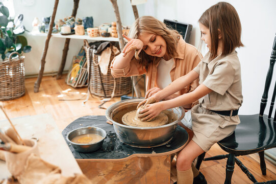 Clay modeling. Mother with little girl doing pottery at home - Powered by Adobe