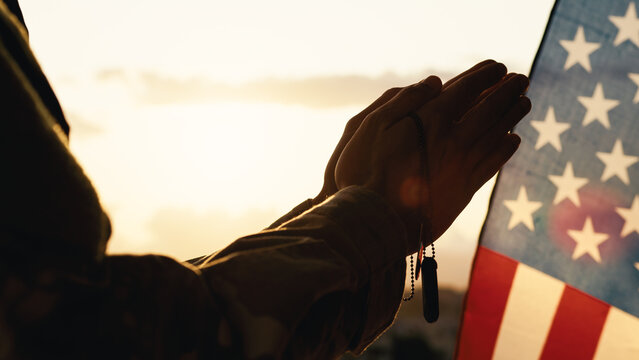 American soldier prays at sunset