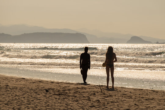 a couple of female silhouettes on a beach at sunset in the summer playing paddleball