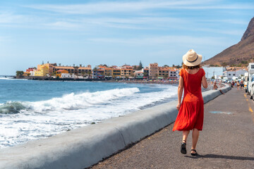 A tourist walking along the promenade on the beach of Valle Gran Rey in La Gomera, Canary Islands © unai