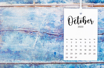 Fototapeta na wymiar The October 2023 calendar page hanged with white rope on old blue wooden background.