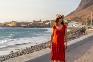 Fototapeta premium Tourist at sunset walking on the beach of the town of Valle Gran Rey in La Gomera, Canary Islands
