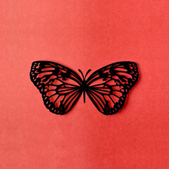 A Black color paper butterfly carve on a red background.