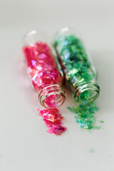 Two glass bottles pink and green glitter used for nail art designs