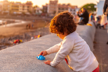 A two year old boy at sunset on vacation on the beach of the town of Valle Gran Rey in La Gomera, Canary Islands. Playing in the sunset by the beach