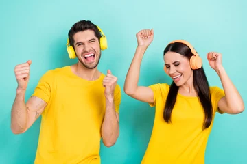 Zelfklevend Fotobehang Portrait of crazy funky overjoyed youngsters listen music test high quality sound bass fists up wear yellow t-shirt isolated on cyan color background © deagreez