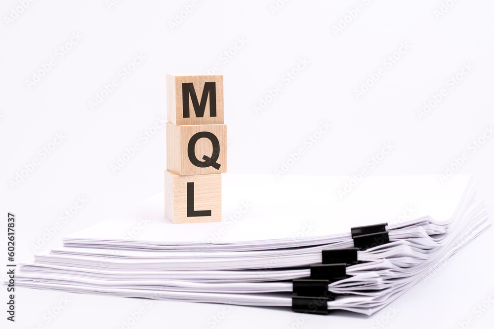 Poster wooden blocks with text mql on white table, stack white paper on background