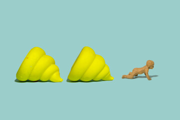 Miniature tiny people toy figure photography. A infant baby newborn crawling beside yellow poop. Isolated on blue background