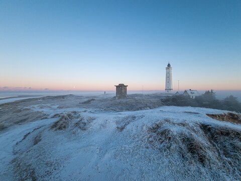 Panorama over the dunes and lighthouse of the Danish coastal resort of Blavand at sunrise