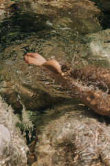 Close-up top view of a young woman's bare feet in a water.