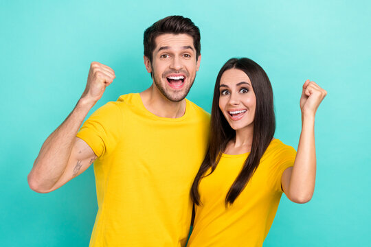 Photo of overjoyed young couple students celebrate bachelor graduation wear promo yellow t-shirts fists up isolated on aquamarine color background
