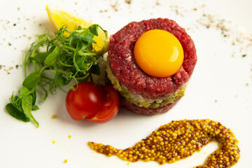 Beef tartar with a egg yolk. French mustard on the side. Top view.
