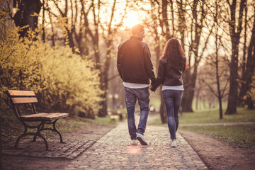 Couple holding hands walking towards sunset. Love theme. Relationship.