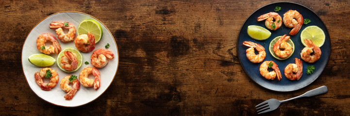 Shrimps, overhead panoramic banner with copy space. Cooked shrimp with lime, shot from the top on a rustic wooden background with a place for text
