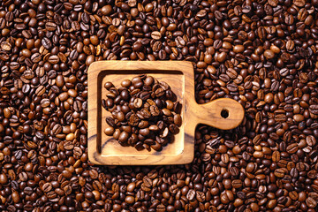 Palone ziarna kawy na całym tle z drewnianą deseczką