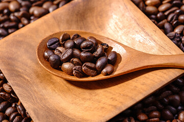 Obraz premium Palone ziarna kawy z drewnianym podstawkiem wypełnionym kawą