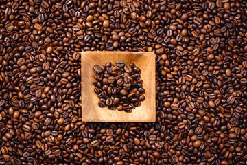 Palone ziarna kawy z drewnianym podstawkiem wypełnionym kawą