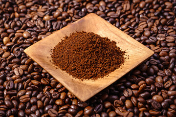 Fototapeta premium Palone ziarna kawy z drewnianym podstawkiem wypełnionym kawą