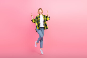 Full body photo of lovely young lady jumping excited show v-sign wear trendy plaid yellow garment isolated on pink color background