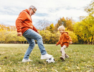 Happy family grandfather and grandson play football on lawn in park. - 602627013
