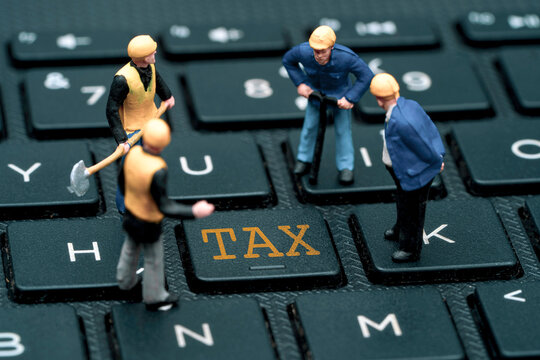 Four worker miniature figure standing and digging on computer keyboard with tax wording , Tax reduction and saving concept.