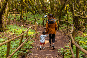 Naklejka na ściany i meble Mother and son next to trees with moss on a trekking in the natural park of Garajonay in La Gomera, Canary Islands