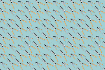 Seamless pattern with gardening tools and garden equipment, pruning shears and scissor with wooden handle, top view isolated on light blue background. Wrapper template for greenhouse or flower shop.