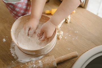 Fototapeta na wymiar Child knead dough, cooks pizza, bake cookies, croissants for mother, father. Little kid daughter having fun cooking pastries or pie on kitchen table top. Family preparation food on weekend. Top view.