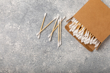 Cotton buds in eco kraft packaging on a textured background. Cotton swab on a white background. Sticks for hygiene of the nose and ears. Bamboo cotton buds. Eco friendly.Place for text.Space for copy.
