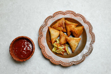 Crispy Samosa filled with chicken and vegetables with chilli sauce tomato ketchup served in dish isolated on table top view of indian, bangladeshi and pakistani street food