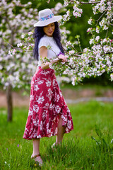 portrait of a beautiful brunette woman in a blossoming apple orchard