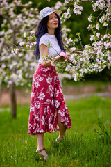 portrait of a beautiful brunette woman in a blossoming apple orchard