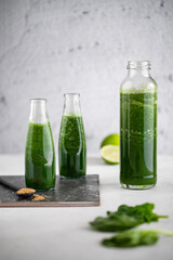 Green smoothie with spinach, banana and lime in small bottles. Raw, vegan, vegetarian, healthy food concept