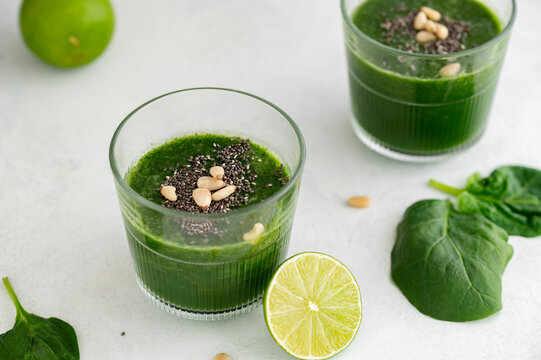 Green smoothie with spinach, banana, lime, chia seeds and pine nuts in a glass. Raw, vegan, vegetarian, healthy food concept
