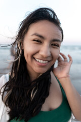 Fototapeta premium Portrait of a young Hispanic woman smiling in front of the sea at the beach