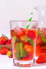 Fototapeta na wymiar Homemade Strawberry lemonade in jar and glass, with many crushed ice, sliced berries and mint leaves, Frozen strawberry sangria, Iced Tea or mojito drink
